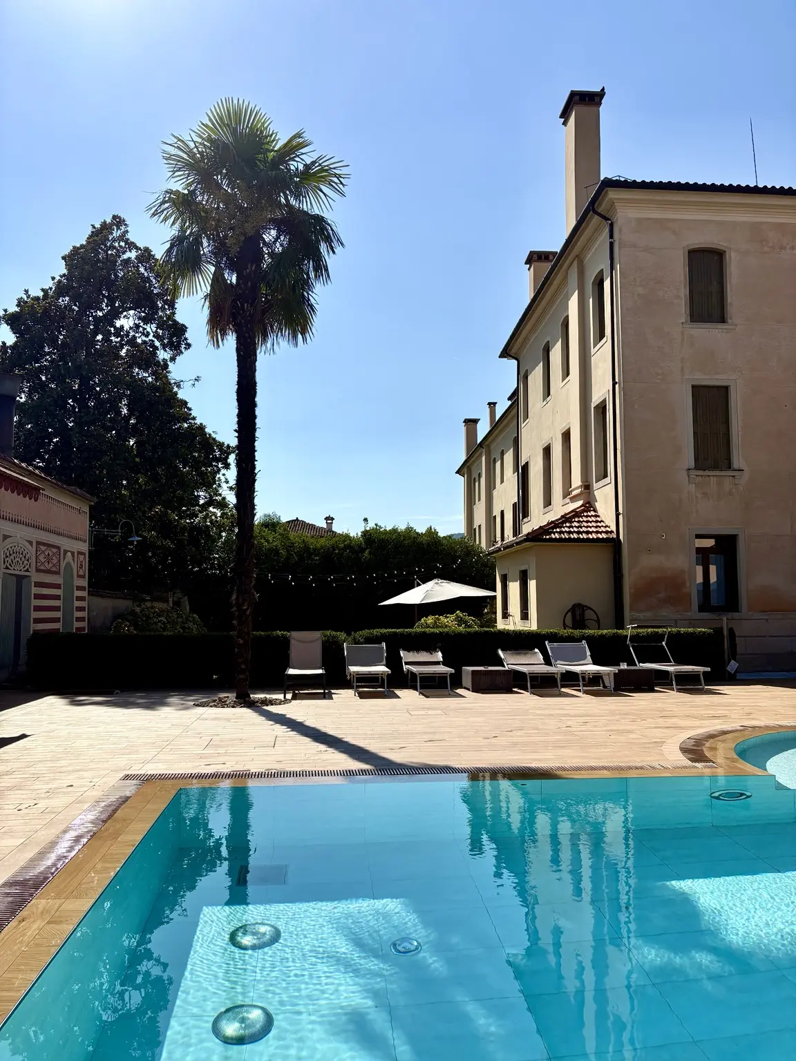 Villa Panigai swimming pool, palm tree and historic villa facade