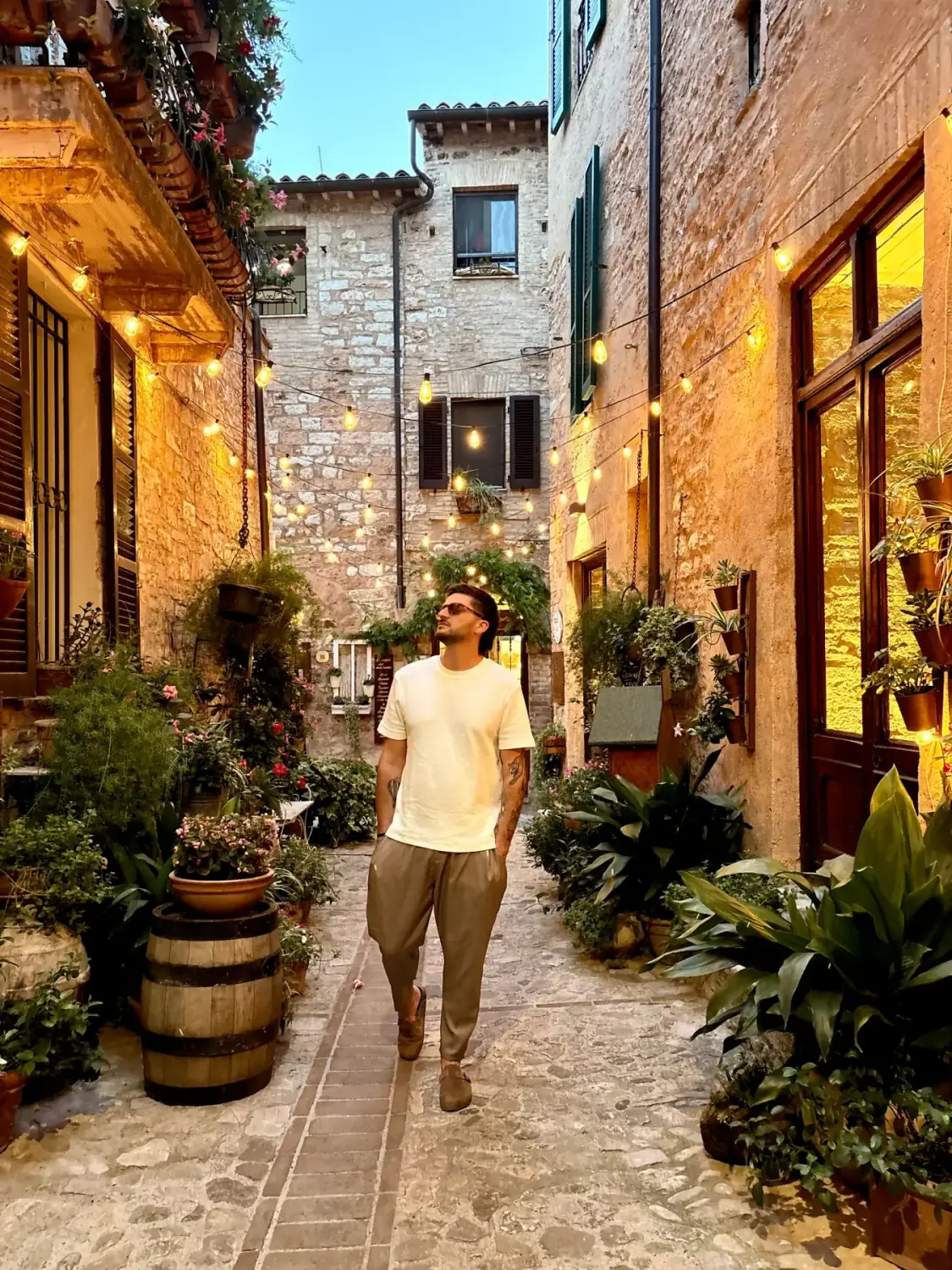 Daniele walking through a flower-lined lane in Spello at dusk