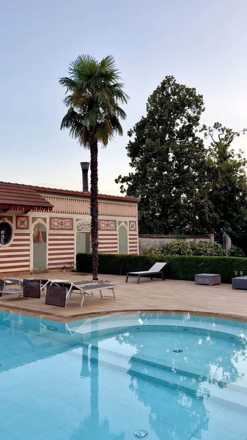 Villa Panigai pool at dusk with palm tree and decorated building